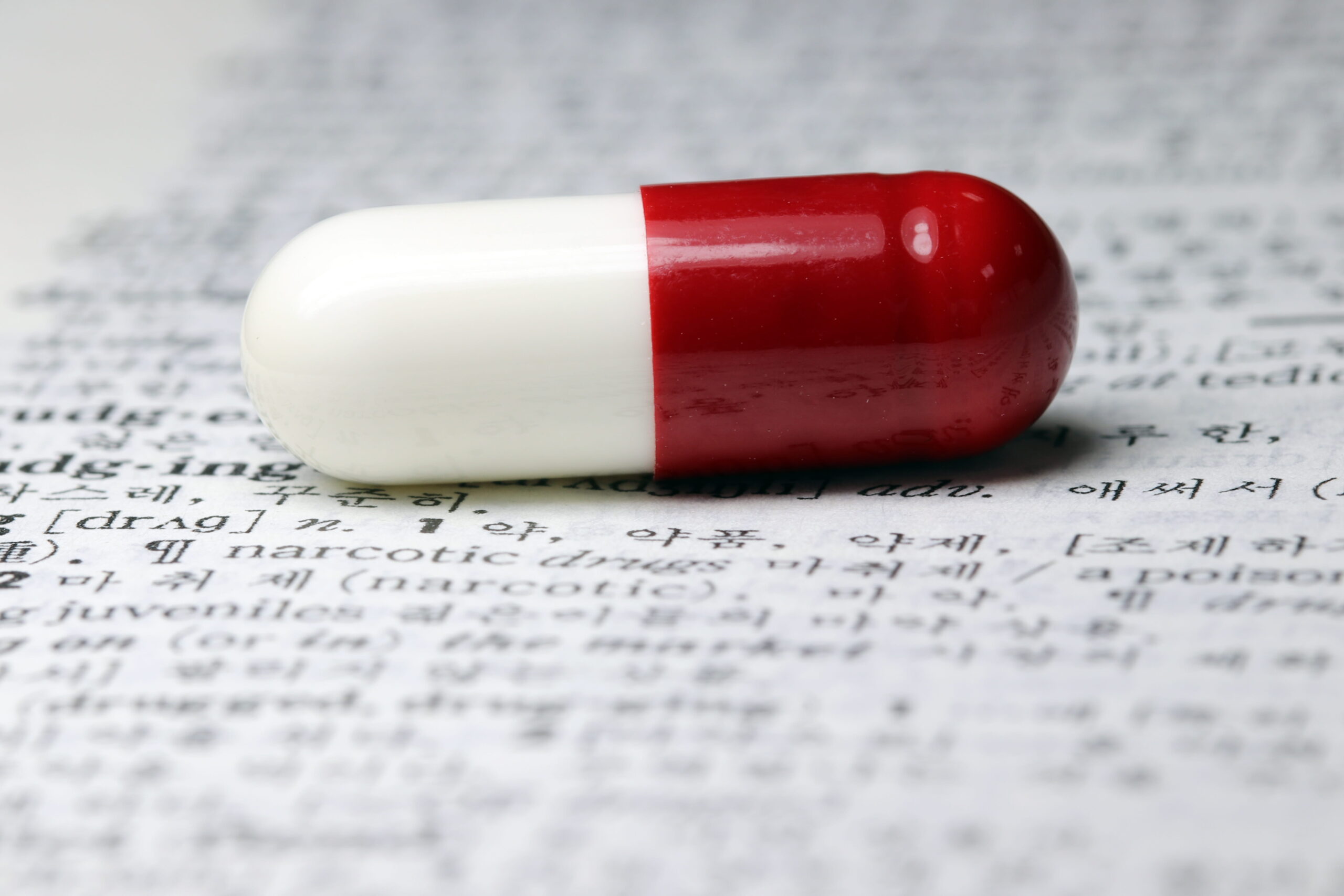 Red and white capsule over unreadable text on a page.